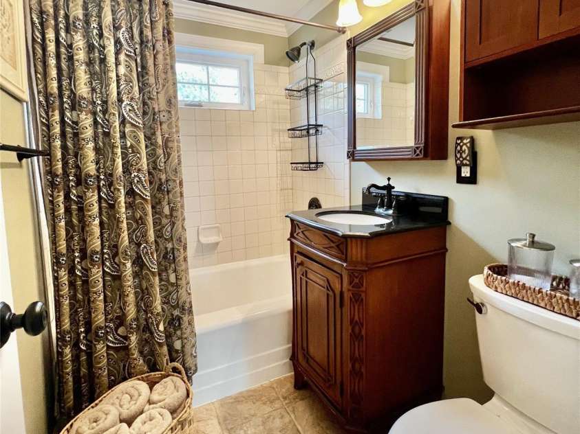 206 Kerlee Heights Road, Black Mountain, NC 28711.  MLS# CAR4414870, YatesRealty ID 47078. The updated bathroom combines cottage warmth with everyday function, featuring a handsome wood vanity, tiled tub surround and convenient storage.