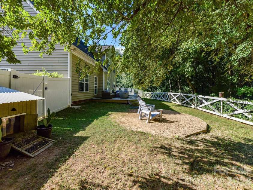 150 Cavendish Drive, Mooresville, NC 28115.  MLS# CAR4416863, YatesRealty ID 47420. Private, tree-lined backyard featuring a spacious lawn, multiple outdoor gathering areas, and a fenced setting ideal for relaxing or entertaining.