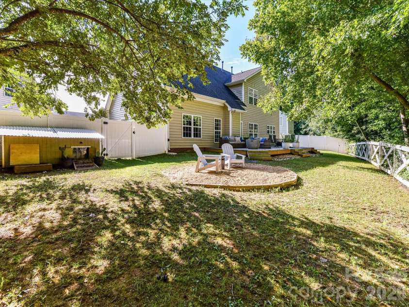 150 Cavendish Drive, Mooresville, NC 28115.  MLS# CAR4416863, YatesRealty ID 47420. Private, tree-lined backyard featuring a spacious lawn, multiple outdoor gathering areas, and a fenced setting ideal for relaxing or entertaining.