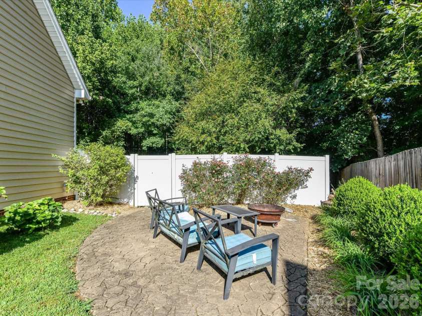 150 Cavendish Drive, Mooresville, NC 28115.  MLS# CAR4416863, YatesRealty ID 47420. Private, tree-lined backyard featuring a spacious lawn, multiple outdoor gathering areas, and a fenced setting ideal for relaxing or entertaining.