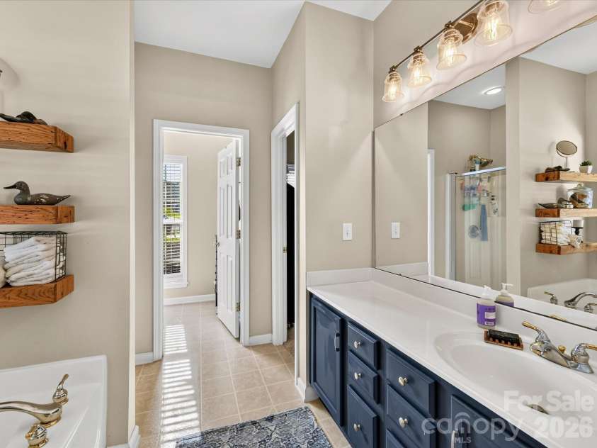 150 Cavendish Drive, Mooresville, NC 28115.  MLS# CAR4416863, YatesRealty ID 47420. Spacious Primary Bath featuring a jetted soaking tub, separate walk-in shower, generous vanity space, built-in shelving, and abundant natural light.
