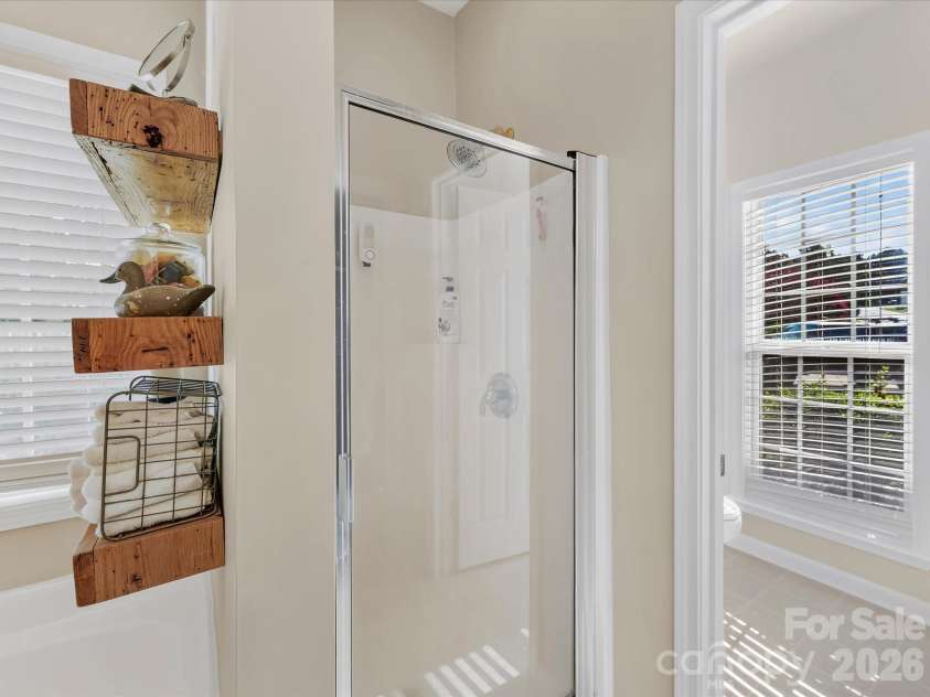 150 Cavendish Drive, Mooresville, NC 28115.  MLS# CAR4416863, YatesRealty ID 47420. Spacious Primary Bath featuring a jetted soaking tub, separate walk-in shower, generous vanity space, built-in shelving, and abundant natural light.