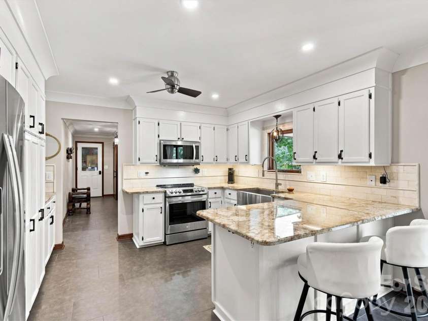 3867 Angie Drive, Denver, NC 28037.  MLS# CAR4413500, YatesRealty ID 47745. Beautifully renovated kitchen featuring tile flooring, granite countertops, tile backsplash, and updated lighting. Includes a stainless steel farmhouse sink, stainless steel appliances (including refrigerator), and updated c