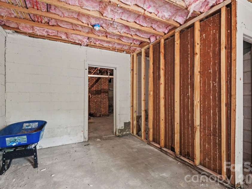 601 Marion Sims Drive, Lancaster, SC 29720.  MLS# CAR4404710, YatesRealty ID 48048. Full unfinished basement with concrete slab flooring, brick support pillars, wire partition storage, and framed areas with exposed studs and insulated ceilings; offering endless potential for a workshop, storage, hom