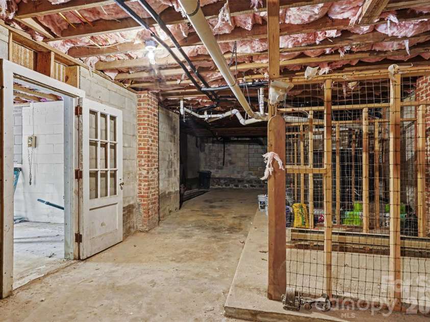 601 Marion Sims Drive, Lancaster, SC 29720.  MLS# CAR4404710, YatesRealty ID 48048. Full unfinished basement with concrete slab flooring, brick support pillars, wire partition storage, and framed areas with exposed studs and insulated ceilings; offering endless potential for a workshop, storage, hom