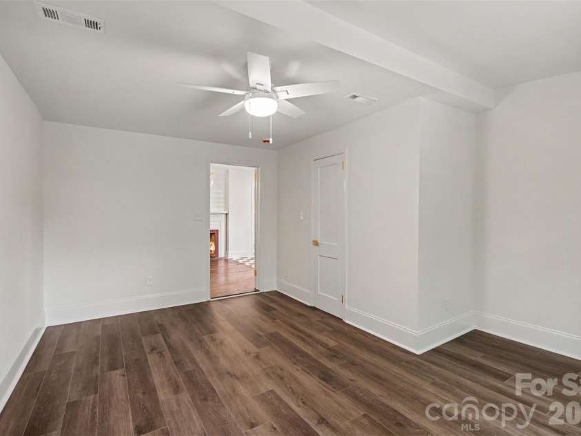 601 Marion Sims Drive, Lancaster, SC 29720.  MLS# CAR4404710, YatesRealty ID 48048. Quiet, light-filled bedroom situated off the kitchen, featuring a large window overlooking lush greenery in the back yard, stylish wide-plank flooring, and a sleek ceiling fan.