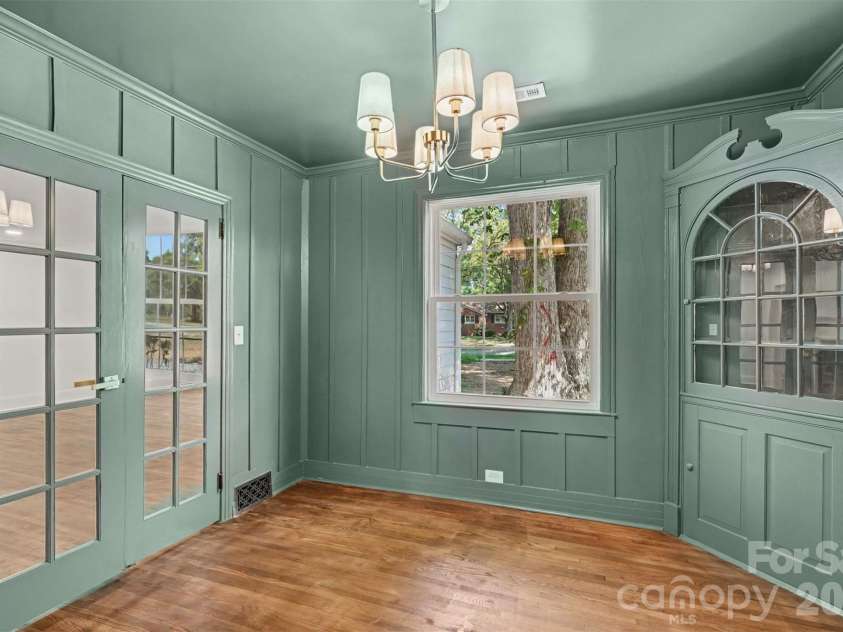 601 Marion Sims Drive, Lancaster, SC 29720.  MLS# CAR4404710, YatesRealty ID 48048. Sunlit dining room or flex space featuring soft ash green walls, custom built-in glass cabinetry, classic French doors, and serene views of the surrounding yard.