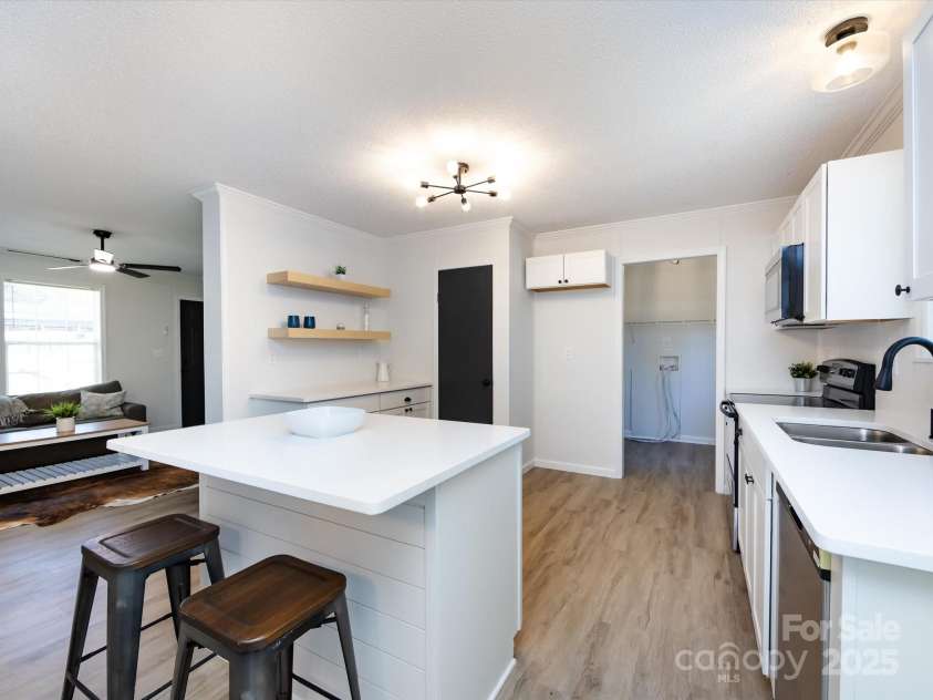 907 4th Avenue, Gastonia, NC 28054.  MLS# CAR4306590, YatesRealty ID 4842. View of kitchen with island, new cabinets, quartz countertops, black fixtures, new hardware, custom farm shelving, & shiplap backsplash.