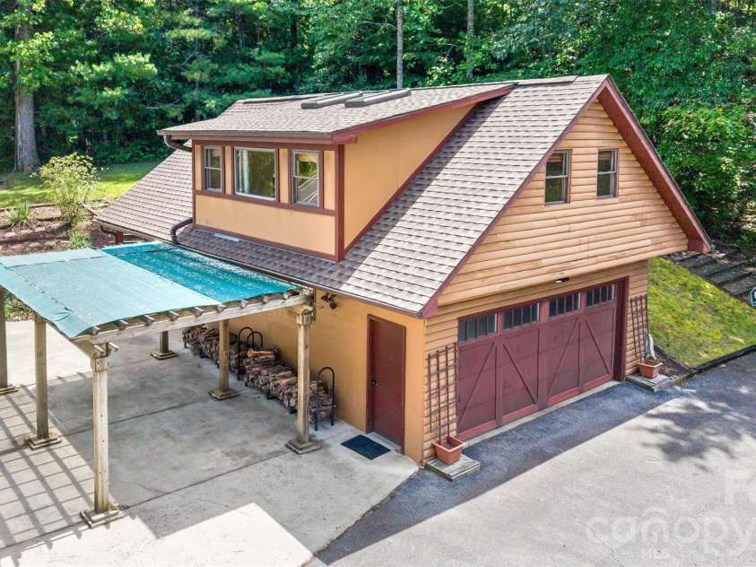16 Spruce Way, Fairview, NC 28730.  MLS# CAR4421539, YatesRealty ID 49354. The separate double garage was thoughtfully designed with a deep bay to accommodate a workbench area.  Additionally, a separate storage room within the main garage is convenient.  Beyond the firewood storage area is another b