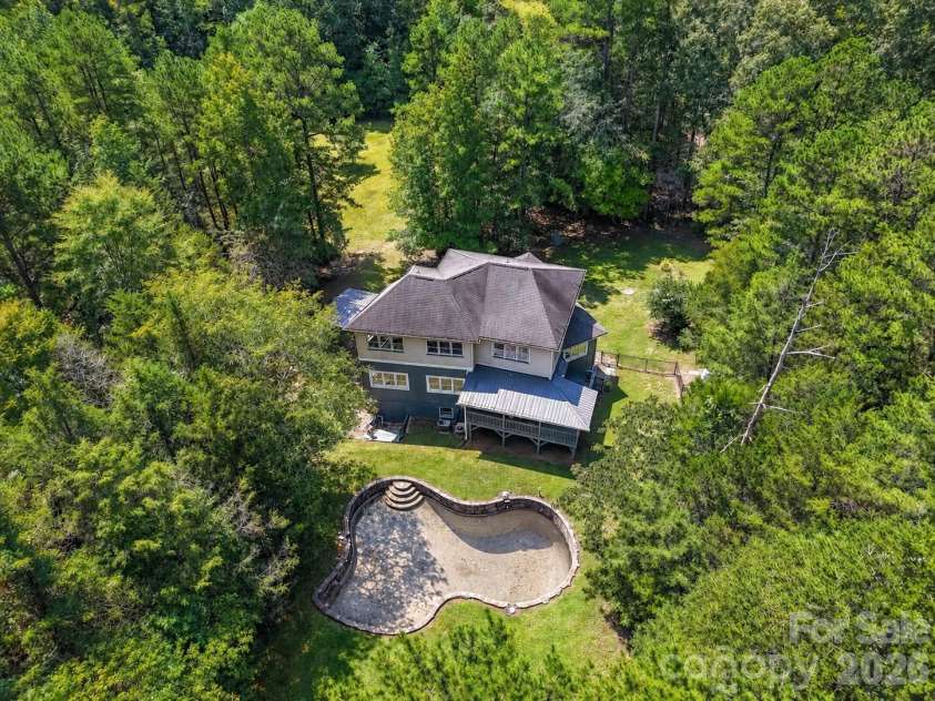 9821 Harvest Lane, Davidson, NC 28036.  MLS# CAR4422485, YatesRealty ID 49465. Aerial view showcases the private wooded setting, spacious backyard, and in-ground pool area surrounding the home.