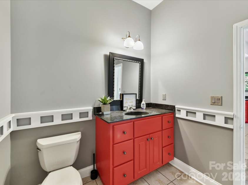 9821 Harvest Lane, Davidson, NC 28036.  MLS# CAR4422485, YatesRealty ID 49465. Convenient main-level powder room with tile flooring, ample vanity storage, and decorative trim details.