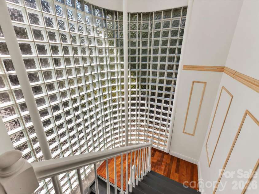 9821 Harvest Lane, Davidson, NC 28036.  MLS# CAR4422485, YatesRealty ID 49465. Dramatic curved floor-to-ceiling glass block wall floods the staircase with natural light, creating a distinctive architectural focal point.