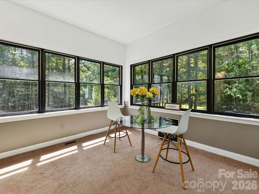 9821 Harvest Lane, Davidson, NC 28036.  MLS# CAR4422485, YatesRealty ID 49465. Light-filled sunroom surrounded by oversized windows showcases tranquil wooded views and the privacy of this expansive Davidson property.