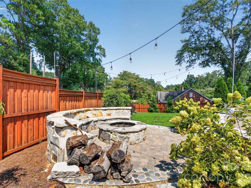 638 Carolina Avenue, Gastonia, NC 28052.  MLS# CAR4421662, YatesRealty ID 49768. A dedicated fire pit area with stone seating, surrounding landscaping, and overhead string lights creates another inviting spot to gather outdoors.