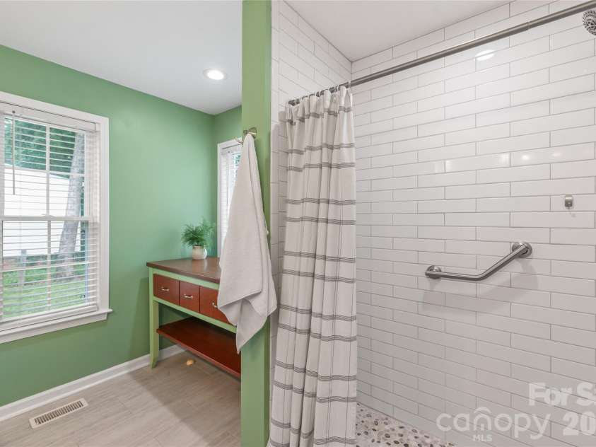 910 Beverly Drive, Rock Hill, SC 29730.  MLS# CAR4421788, YatesRealty ID 49769. A spacious walk-in shower featuring a tile surround that extends all the way to the ceiling, plus dedicated space for a tub with plumbing neatly concealed beneath a custom furniture piece.
