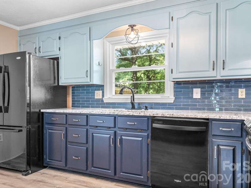316 Hudson Drive, Harrisburg, NC 28075.  MLS# CAR4420210, YatesRealty ID 49798. Renovated kitchen with granite counters, appliances including gas range, and refrigerator.