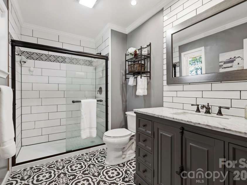 168 Country Lane, Mills River, NC 28759.  MLS# CAR4422309, YatesRealty ID 49874. Beautifully updated ensuite bath features a tiled walk-in shower, patterned tile flooring, substantial vanity, and stylish finishes.