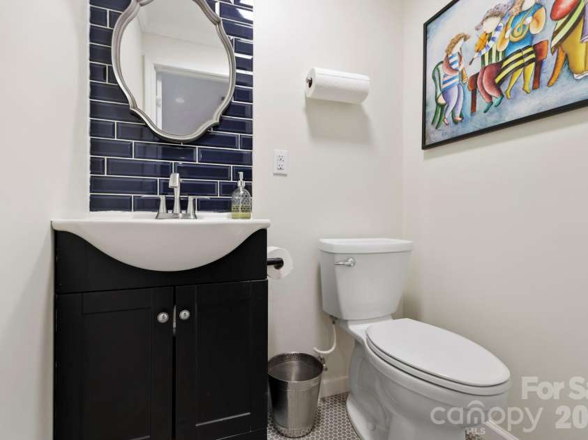 168 Country Lane, Mills River, NC 28759.  MLS# CAR4422309, YatesRealty ID 49874. Convenient lower-level half bath features a stylish vanity, tile accent wall, and modern fixtures.