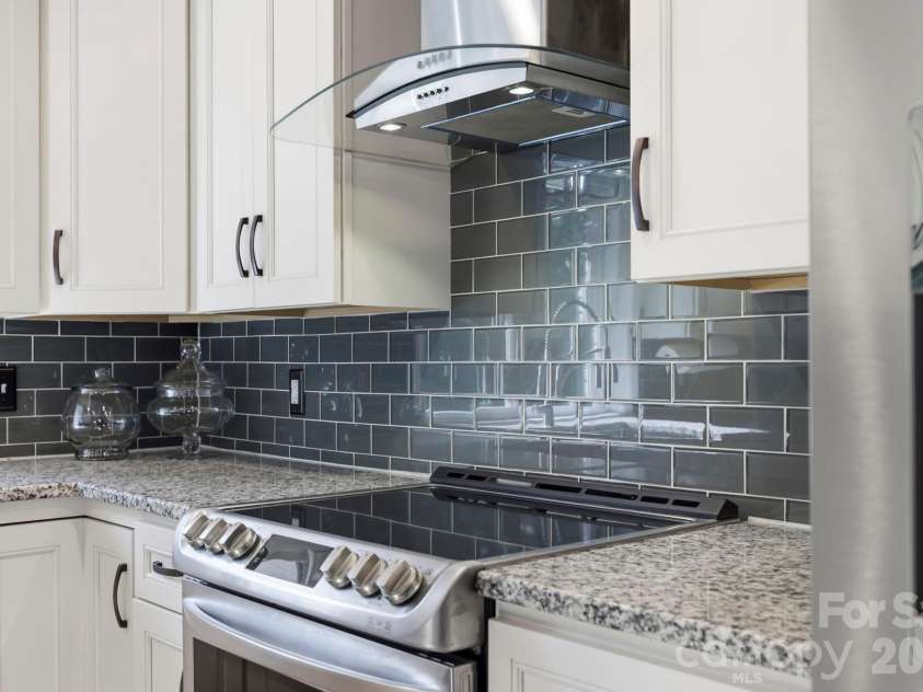168 Country Lane, Mills River, NC 28759.  MLS# CAR4422309, YatesRealty ID 49874. Stylish tile backsplash, sleek range hood, and stainless range highlight the thoughtful updates throughout the kitchen.