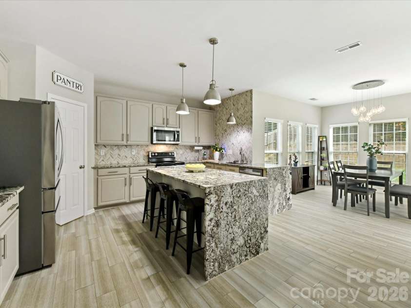 9338 Atlas Cedar Drive, Charlotte, NC 28215.  MLS# CAR4422993, YatesRealty ID 49889. Updated kitchen features granite waterfall countertops, refreshed cabinetry, modern hardware, backsplash, and a large center island with seating.