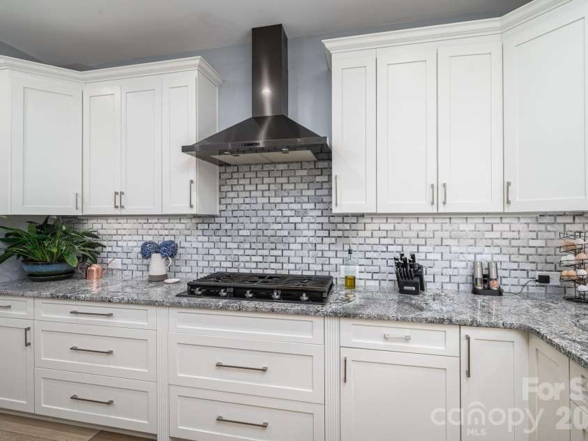 1551 Brevard Place Road, Iron Station, NC 28080.  MLS# CAR4422440, YatesRealty ID 50132. Kitchen featuring a gas cooktop, vented range hood, granite countertops, tile backsplash, and abundant cabinetry.