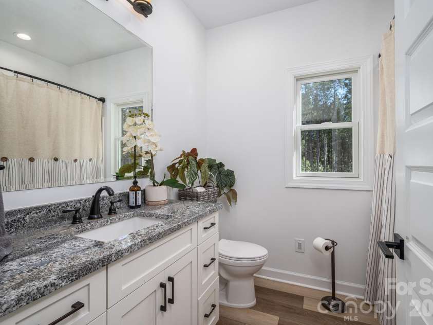 1551 Brevard Place Road, Iron Station, NC 28080.  MLS# CAR4422440, YatesRealty ID 50132. Main-level full bathroom featuring a spacious vanity with granite countertop, with bathtub and shower.