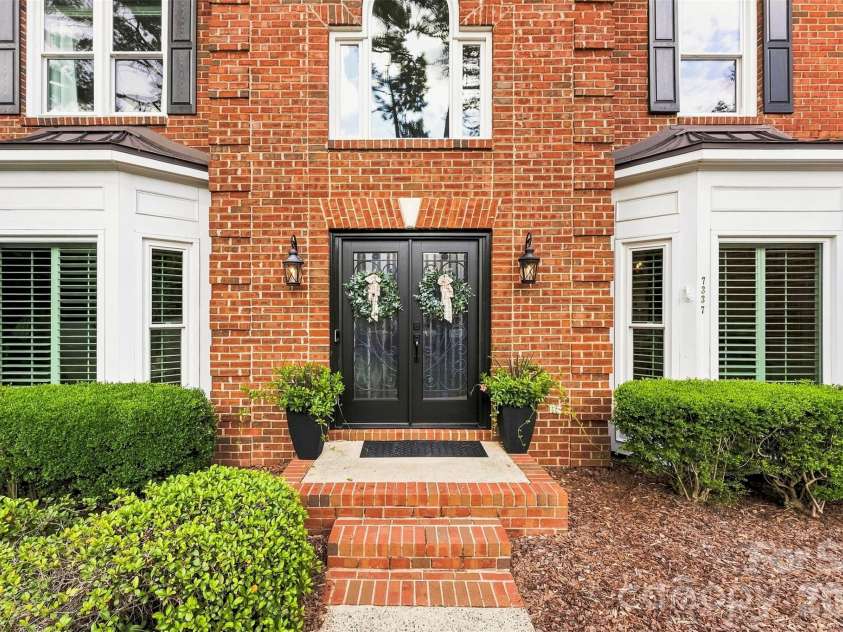 7337 Versailles Lane, Charlotte, NC 28277.  MLS# CAR4418758, YatesRealty ID 50195. Twin bay windows, brick steps, and manicured landscaping create a classically elegant approach to the home
