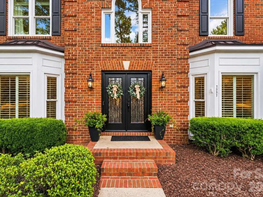 7337 Versailles Lane, Charlotte, NC 28277.  MLS# CAR4418758, YatesRealty ID 50195. Twin bay windows, brick steps, and manicured landscaping create a classically elegant approach to the home