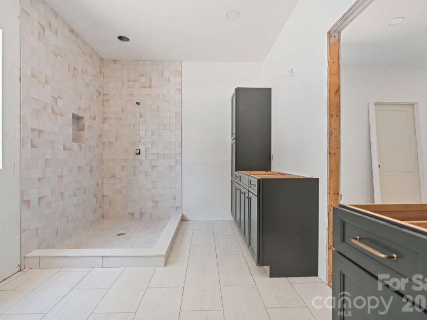 6395 Wingate Hill Road, Denver, NC 28037.  MLS# CAR4423290, YatesRealty ID 50281. This primary bath has separate vanities, each with their own closets.  The pretty tile shower, frameless glass, and soaking tub complete the space.