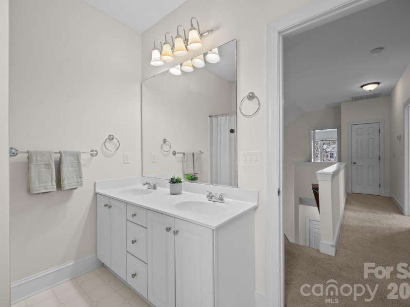 100 Martin Street, Davidson, NC 28036.  MLS# CAR4341669, YatesRealty ID 5062. It features a practical and efficient setup with a dual vanity, which provides two separate sinks and ample counter space for shared use, complete with dedicated storage below. For bathing, the room includes a classic show