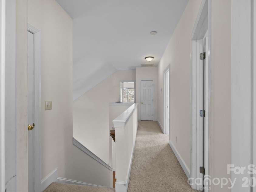 100 Martin Street, Davidson, NC 28036.  MLS# CAR4341669, YatesRealty ID 5062. This home features an impressive long stairway that serves as a central vertical element that culminates on the second level, opening directly into the upstairs hall, which is the central access point to the private bedroo