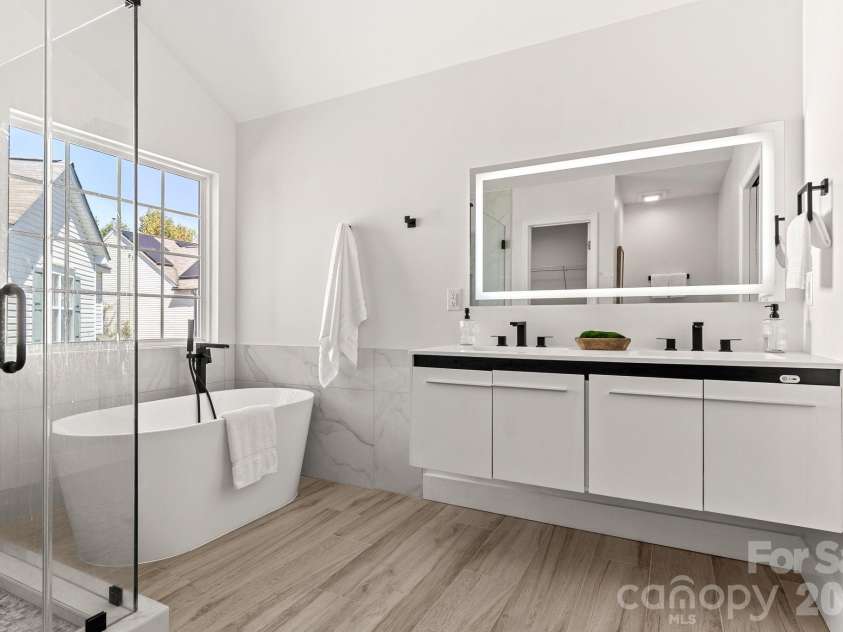 1153 Delander Lane, Charlotte, NC 28214.  MLS# CAR4424709, YatesRealty ID 51391. Gorgeous modern primary bathroom with floating shovels and backlit mirror
