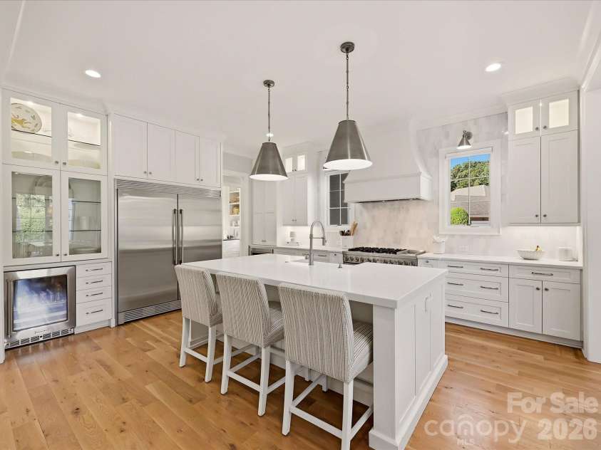 18717 Square Sail Road, Cornelius, NC 28031.  MLS# CAR4424933, YatesRealty ID 51420. Bright designer kitchen features an oversized island with seating, custom cabinetry, stainless steel appliances, a statement range hood, beverage refrigerator, and abundant workspace for everyday living and entertai