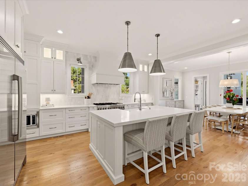 18717 Square Sail Road, Cornelius, NC 28031.  MLS# CAR4424933, YatesRealty ID 51420. Bright designer kitchen features an oversized island with seating, custom cabinetry, stainless steel appliances, a statement range hood, beverage refrigerator, and abundant workspace for everyday living and entertai