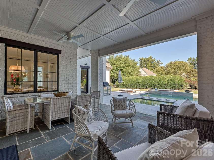 18717 Square Sail Road, Cornelius, NC 28031.  MLS# CAR4424933, YatesRealty ID 51420. Expansive covered back patio extends the living space outdoors with a fireplace, ceiling fans, dining and lounge areas, and seamless access to the private pool.