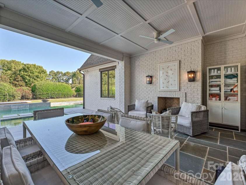 18717 Square Sail Road, Cornelius, NC 28031.  MLS# CAR4424933, YatesRealty ID 51420. Expansive covered back patio extends the living space outdoors with a fireplace, ceiling fans, dining and lounge areas, and seamless access to the private pool.