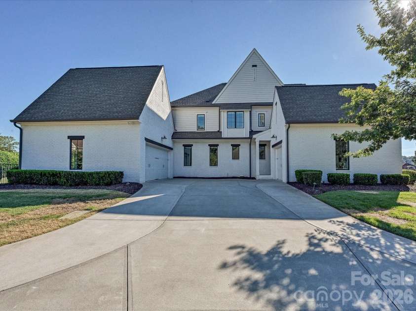 18717 Square Sail Road, Cornelius, NC 28031.  MLS# CAR4424933, YatesRealty ID 51420. Impressive exterior showcases timeless white-brick architecture, manicured landscaping, and a spacious two-car garage with a broad driveway for convenient parking and access.