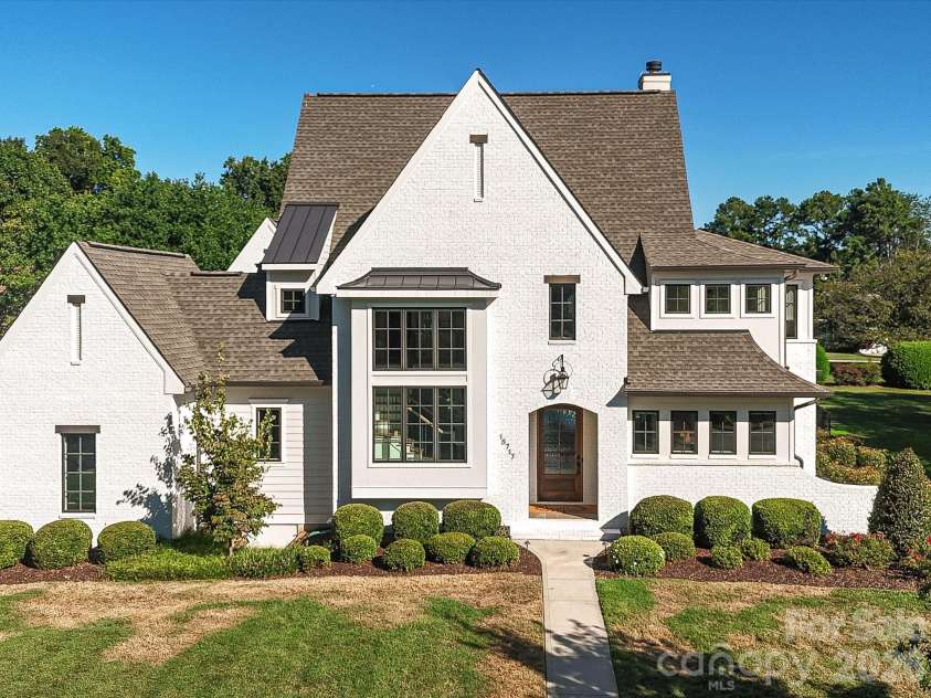 18717 Square Sail Road, Cornelius, NC 28031.  MLS# CAR4424933, YatesRealty ID 51420. Impressive exterior showcases timeless white-brick architecture, manicured landscaping, and a spacious two-car garage with a broad driveway for convenient parking and access.