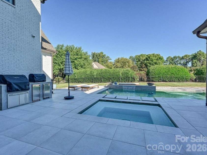 18717 Square Sail Road, Cornelius, NC 28031.  MLS# CAR4424933, YatesRealty ID 51420. Resort-style backyard showcases a sleek, salt water, heated pool and spa with waterfall feature, expansive patio space, and a private setting ideal for outdoor entertaining and relaxation.