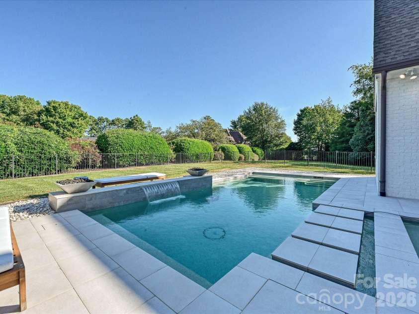 18717 Square Sail Road, Cornelius, NC 28031.  MLS# CAR4424933, YatesRealty ID 51420. Resort-style backyard showcases a sleek, salt water, heated pool and spa with waterfall feature, expansive patio space, and a private setting ideal for outdoor entertaining and relaxation.