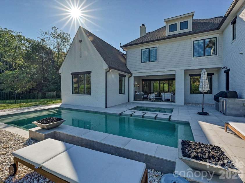 18717 Square Sail Road, Cornelius, NC 28031.  MLS# CAR4424933, YatesRealty ID 51420. Resort-style backyard showcases a sleek, salt water, heated pool and spa with waterfall feature, expansive patio space, and a private setting ideal for outdoor entertaining and relaxation.