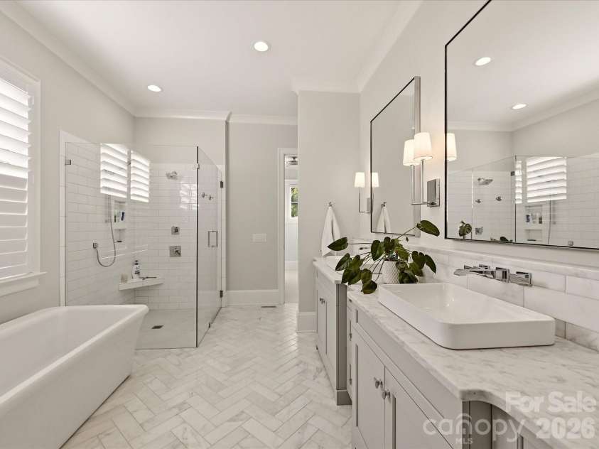 18717 Square Sail Road, Cornelius, NC 28031.  MLS# CAR4424933, YatesRealty ID 51420. Spa-inspired Primary Bath features a freestanding soaking tub, oversized frameless glass shower, dual vanities with stone countertops, and elegant herringbone-patterned tile flooring.
