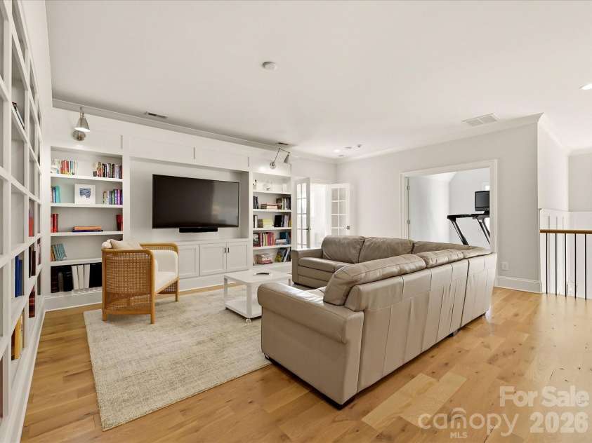 18717 Square Sail Road, Cornelius, NC 28031.  MLS# CAR4424933, YatesRealty ID 51420. Spacious upper-level loft offers built-in shelving, abundant natural light, and flexible space ideal for a media room, lounge, or casual gathering area.