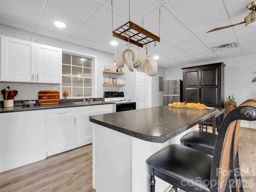 27 & 56 Troy Lane, Tryon, NC 28782.  MLS# CAR4426480, YatesRealty ID 52041. Light bright full kitchen has an island with storage and a breakfast bar.