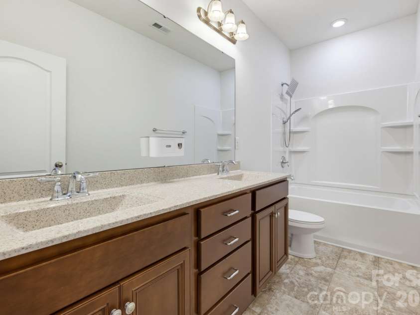 8315 Breton Way, Harrisburg, NC 28075.  MLS# CAR4426522, YatesRealty ID 52653. The second-level en suite bathroom includes double sinks, a tub-and-shower combination, and built-in shower shelving for everyday storage.