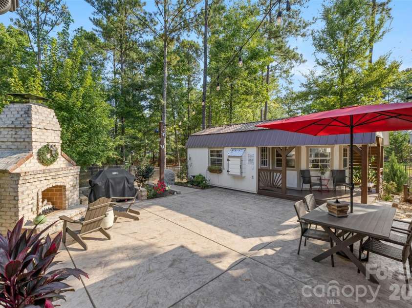 1604 Aragon Beach Road, Rock Hill, SC 29732.  MLS# CAR4427159, YatesRealty ID 52944. Spacious patio with an outdoor fireplace, dining area, and string lights for entertaining