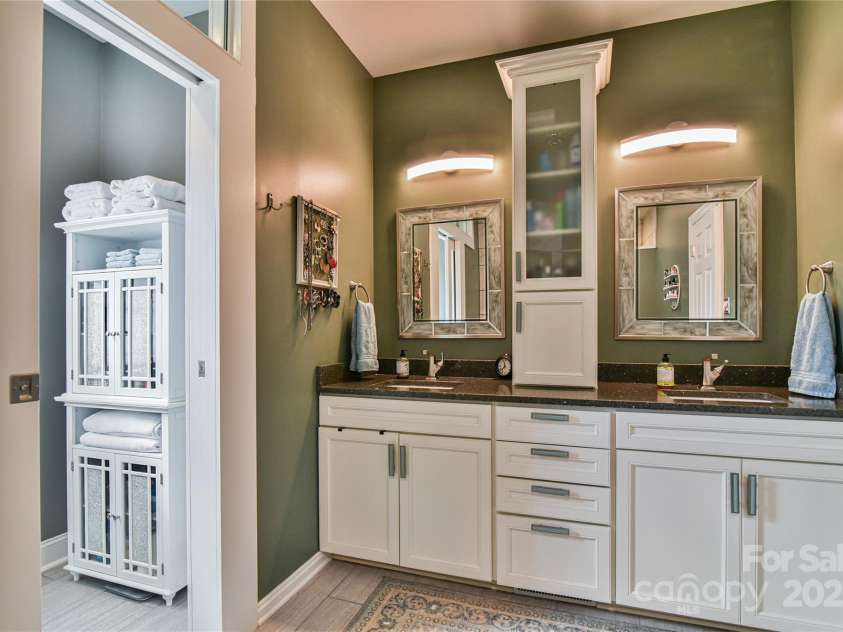 79 Pattys Chapel Road, Fletcher, NC 28732.  MLS# CAR4239671, YatesRealty ID 5295. Primary bath with dual sink vanity, linen tower, and private water closet to the left with etched glass pocket door.