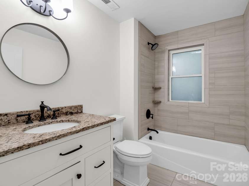 145 Stone Hedge Lane, Tryon, NC 28782.  MLS# CAR4428268, YatesRealty ID 53072. Guest bathroom with tile and solid surface vanity top