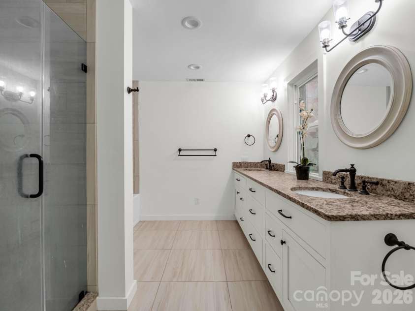 145 Stone Hedge Lane, Tryon, NC 28782.  MLS# CAR4428268, YatesRealty ID 53072. Primary tile bathroom with shower and tub, double vanity and solid surface counters