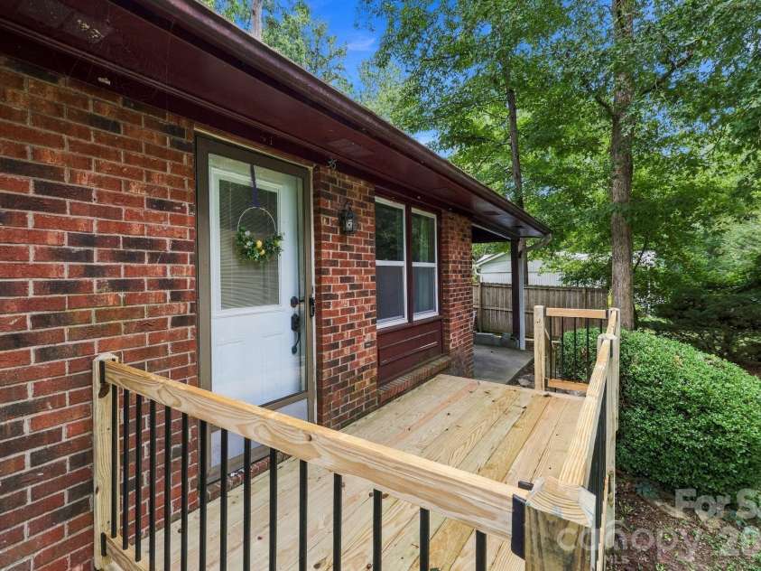36 Medlin Lane, Flat Rock, NC 28731.  MLS# CAR4428597, YatesRealty ID 53594. Front entry features a recently updated wood deck with black metal railing.